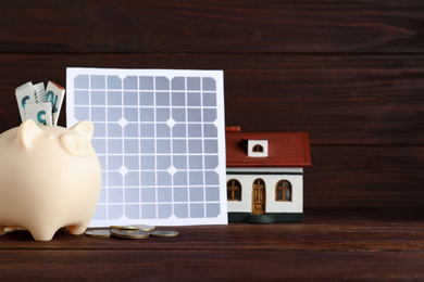 Photo of Composition with solar panel and piggy bank on wooden table