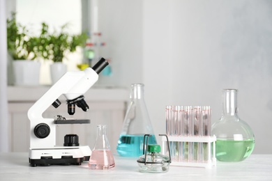 Laboratory glassware and microscope on table indoors. Chemistry concept