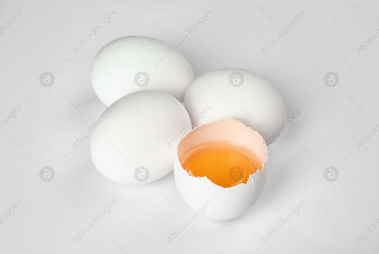 Photo of Cracked and whole chicken eggs on white background