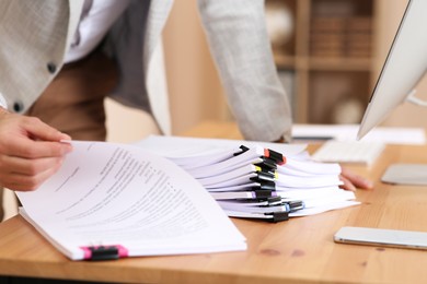 Photo of Man working with documents at wooden table in office, closeup