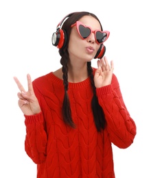 Young woman wearing heart shaped glasses listening to music on white background