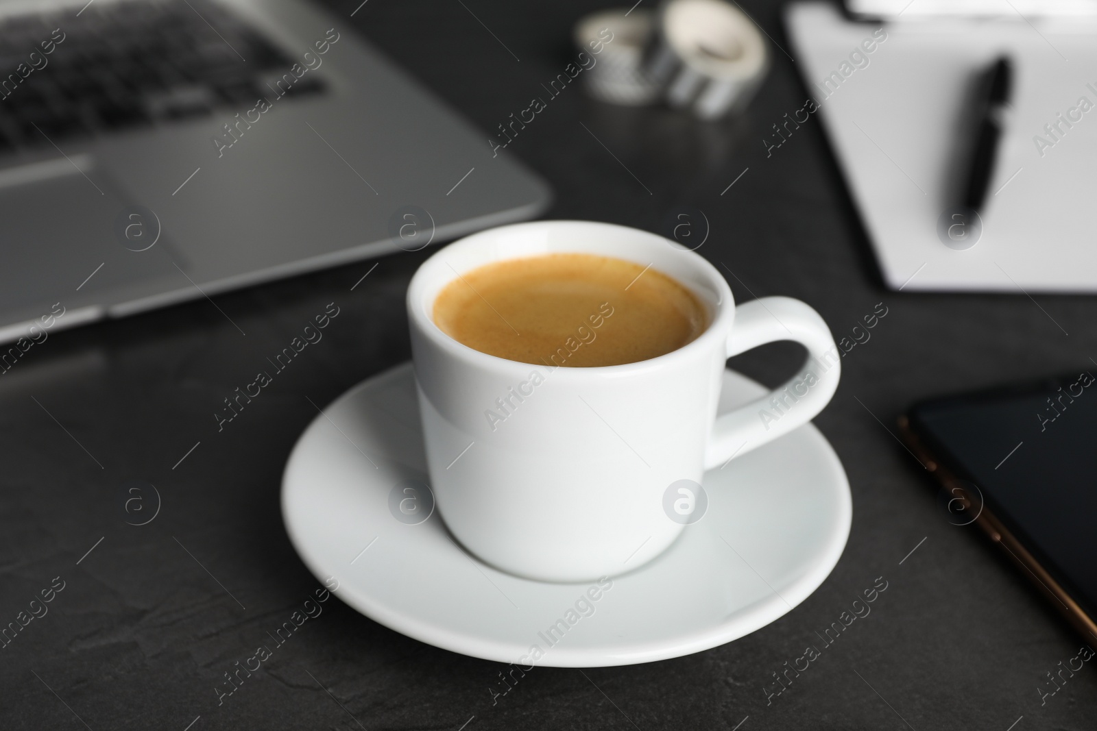 Photo of Coffee Break at workplace. Cup of hot espresso on grey table