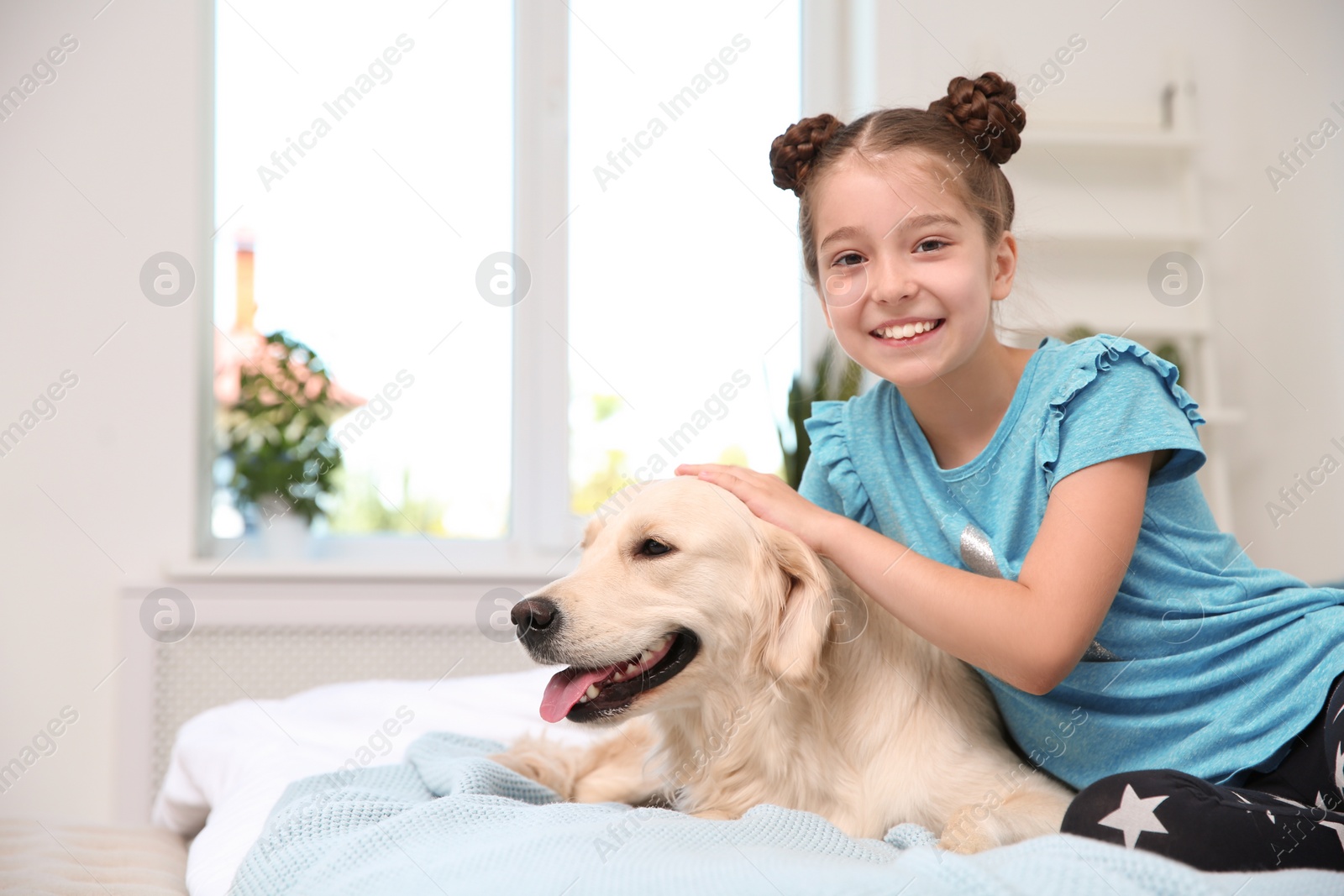 Photo of Cute little child with her pet on bed at home