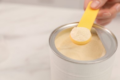 Photo of Woman with powdered infant formula at table, closeup and space for text. Preparing baby milk