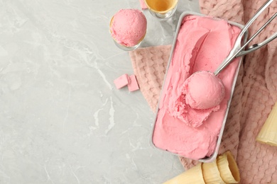 Delicious ice cream in container and wafer cones on light grey table, flat lay. Space for text