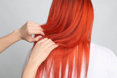 Woman with bright dyed hair on grey background, back view