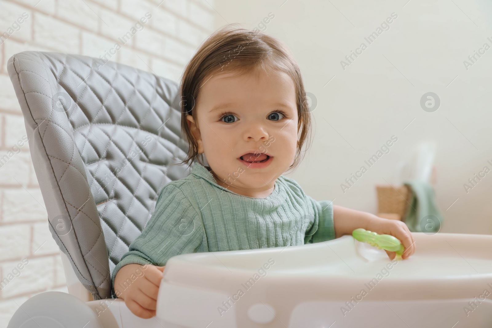 Photo of Cute little baby with teether in high chair indoors