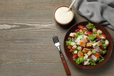 Photo of Delicious fresh Caesar salad on wooden table, flat lay. Space for text