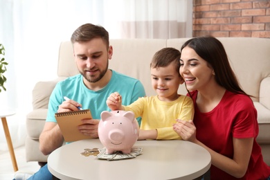 Photo of Happy family with piggy bank and money at home