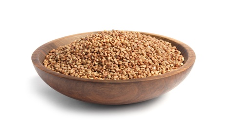 Bowl with uncooked buckwheat on white background