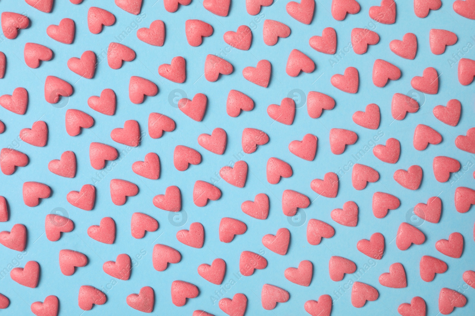 Photo of Bright heart shaped sprinkles on light blue background, flat lay