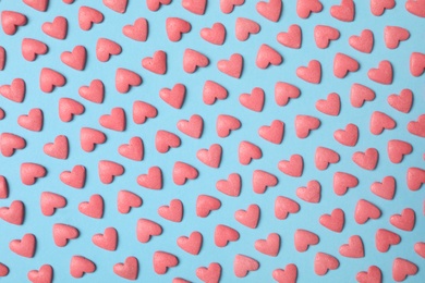 Photo of Bright heart shaped sprinkles on light blue background, flat lay