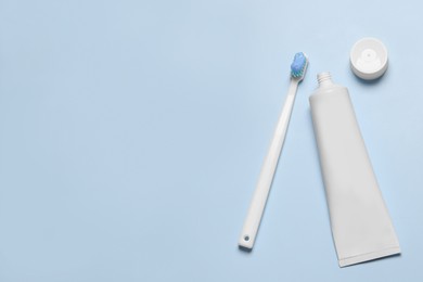 Plastic toothbrush with paste and tube on light background, flat lay. Space for text