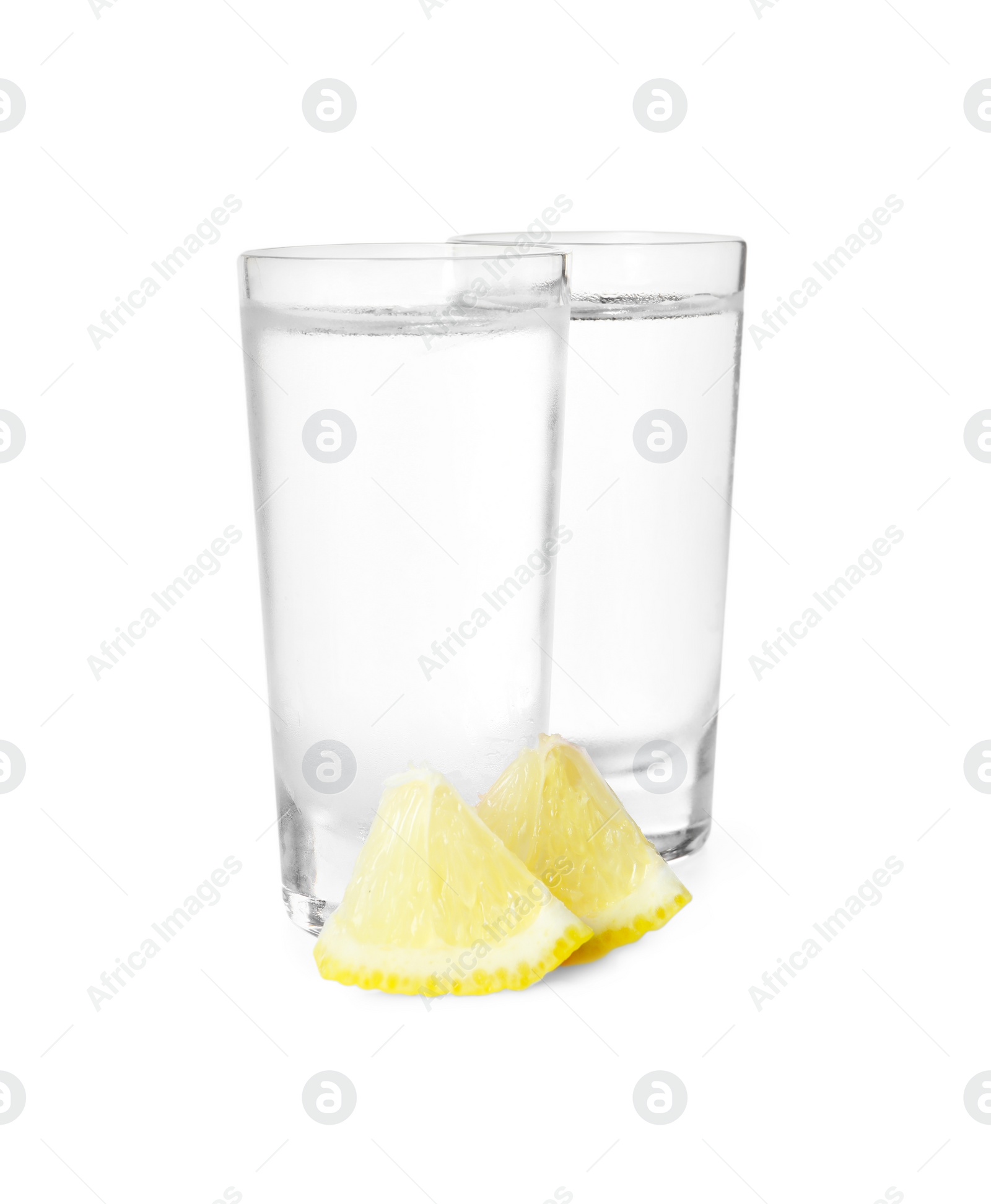 Photo of Shot glasses of vodka with lemon slices on white background