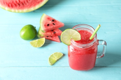 Tasty summer watermelon drink in mason jar and sliced fruits on table