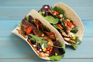 Delicious tacos with fried bacon, vegetables and cheese on turquoise wooden table, closeup