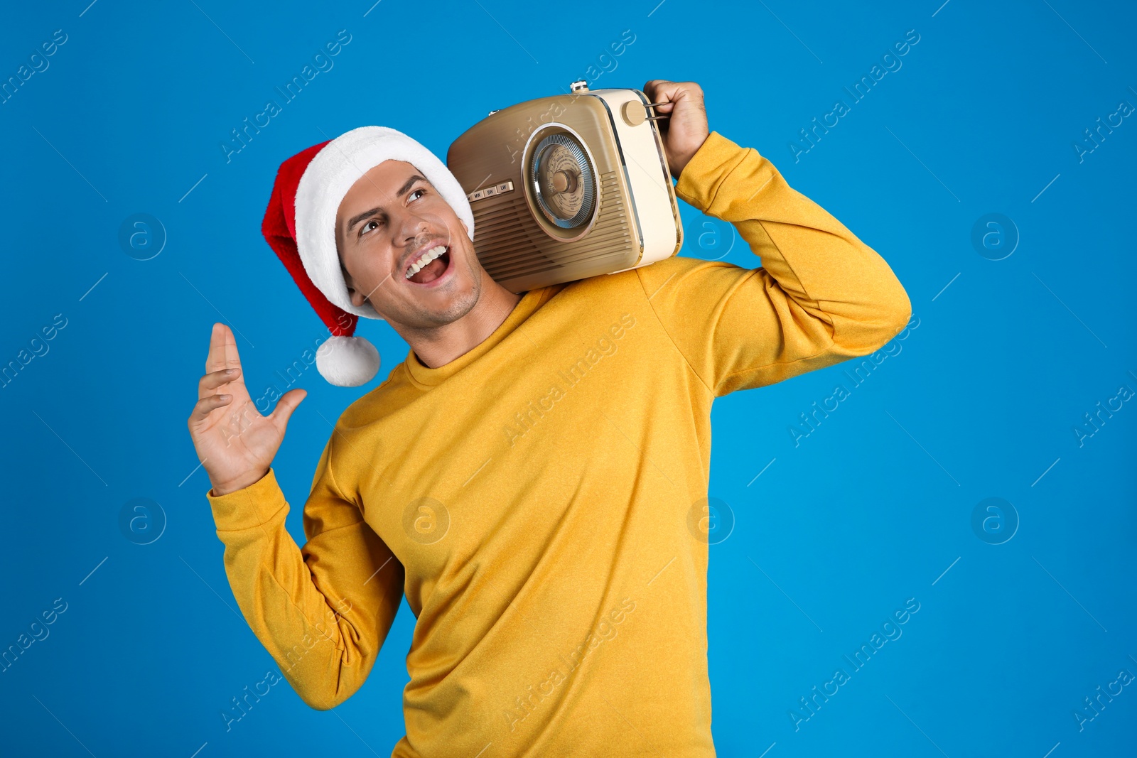 Photo of Emotional man with vintage radio on blue background. Christmas music