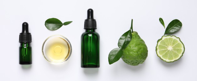 Photo of Bergamot essential oil and fresh fruits on white background, flat lay
