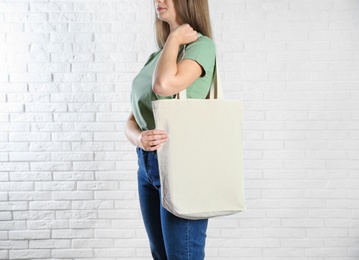 Photo of Woman with eco bag near brick wall. Mock up for design