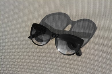 Photo of Stylish sunglasses on grey surface. Beach accessory, above view