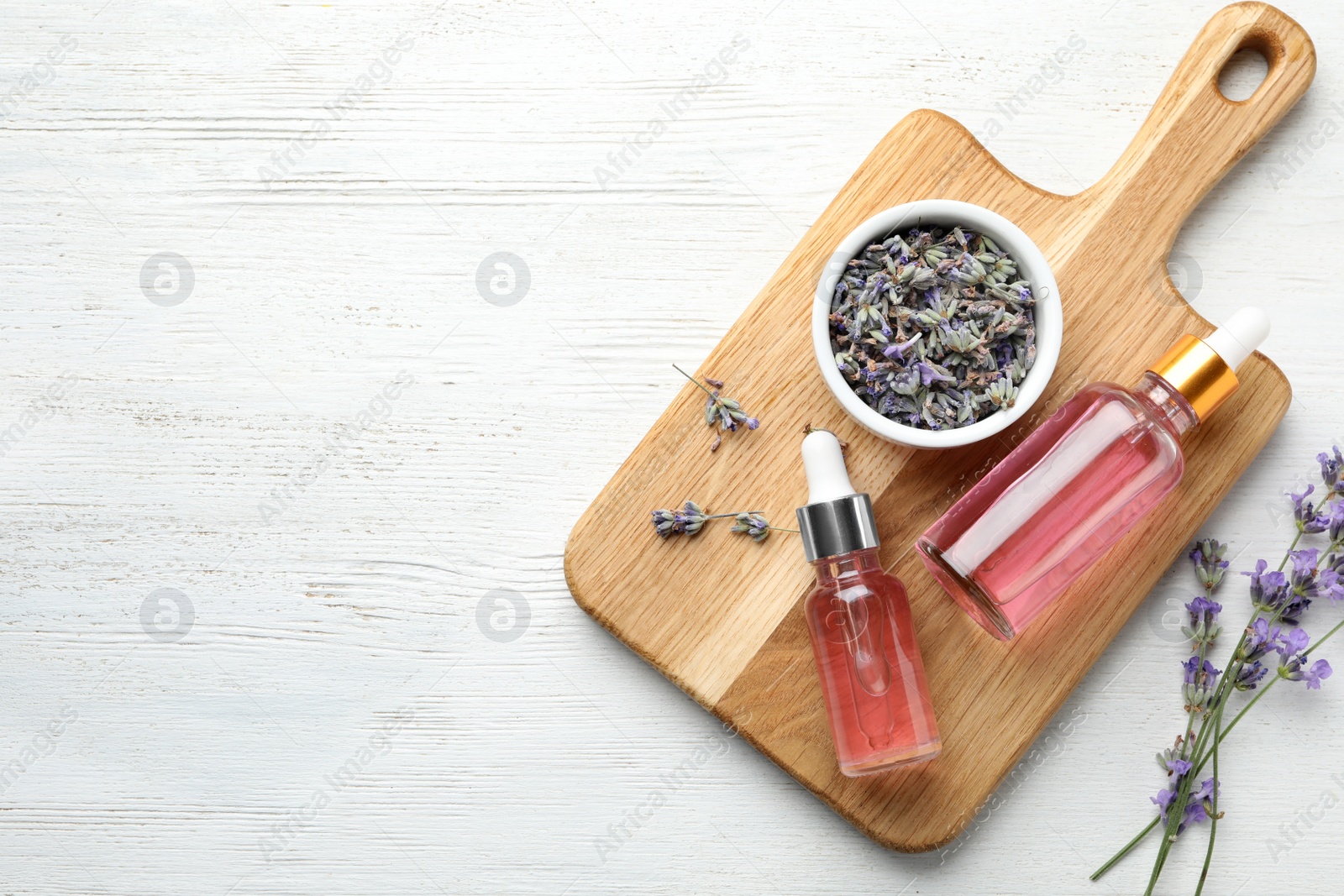 Photo of Flat lay composition with bottles of natural lavender essential oil on white wooden background. Space for text