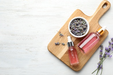 Photo of Flat lay composition with bottles of natural lavender essential oil on white wooden background. Space for text