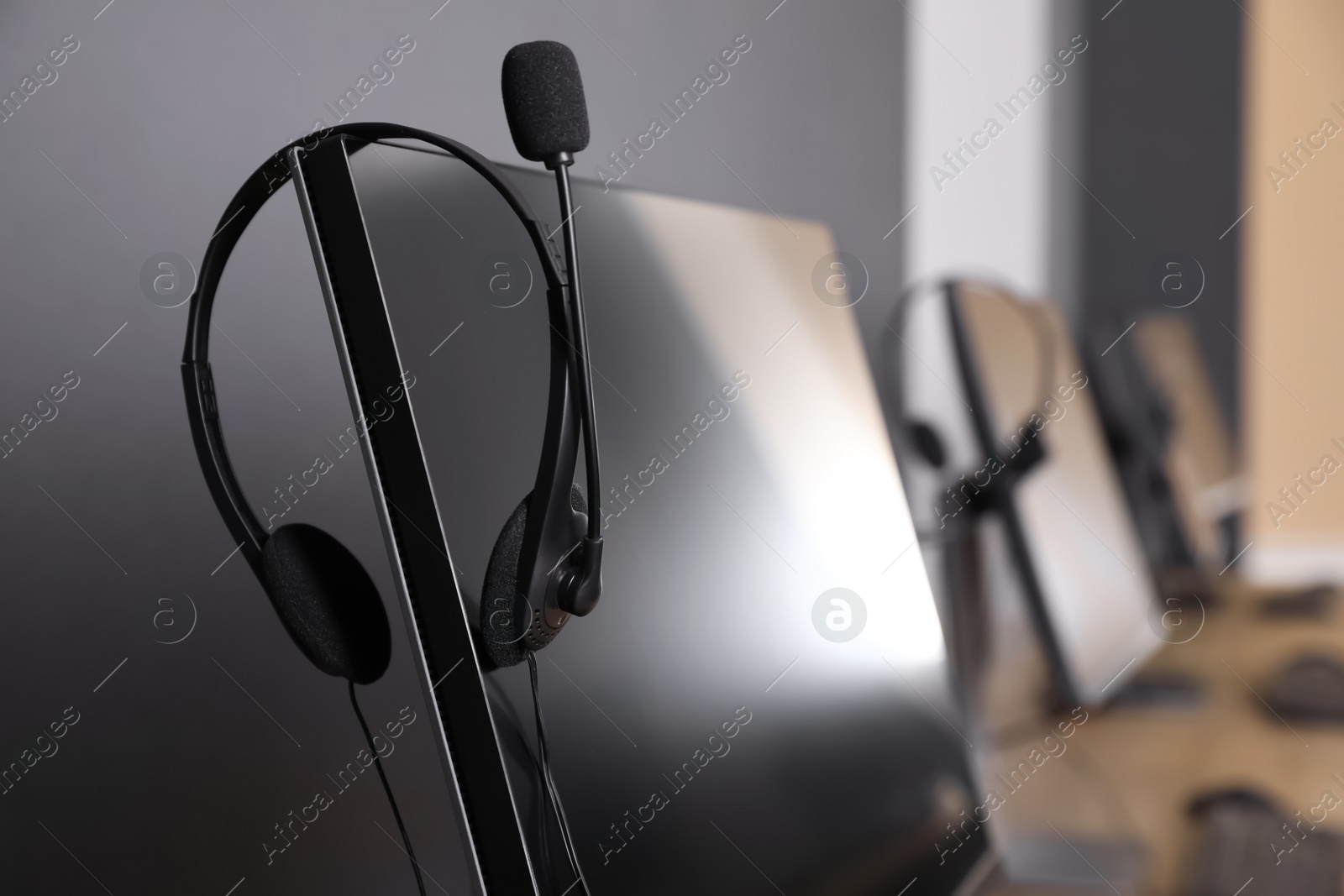 Photo of Modern computer with headset in office, closeup. Hotline service