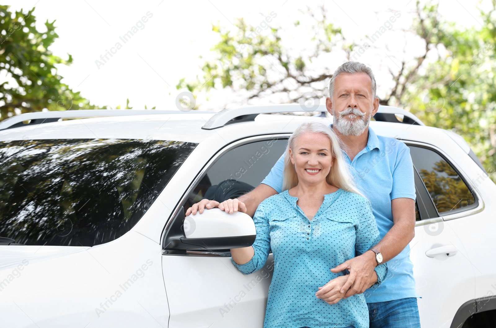 Photo of Happy senior couple posing near car outdoors