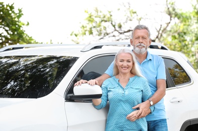 Photo of Happy senior couple posing near car outdoors