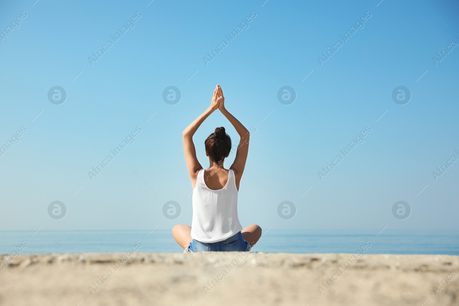 Photo of Beautiful young woman practicing yoga near sea