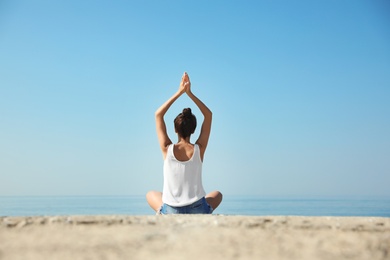 Photo of Beautiful young woman practicing yoga near sea