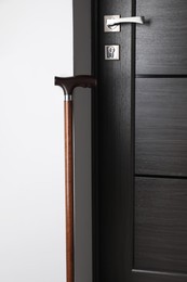Elegant wooden walking cane near door indoors