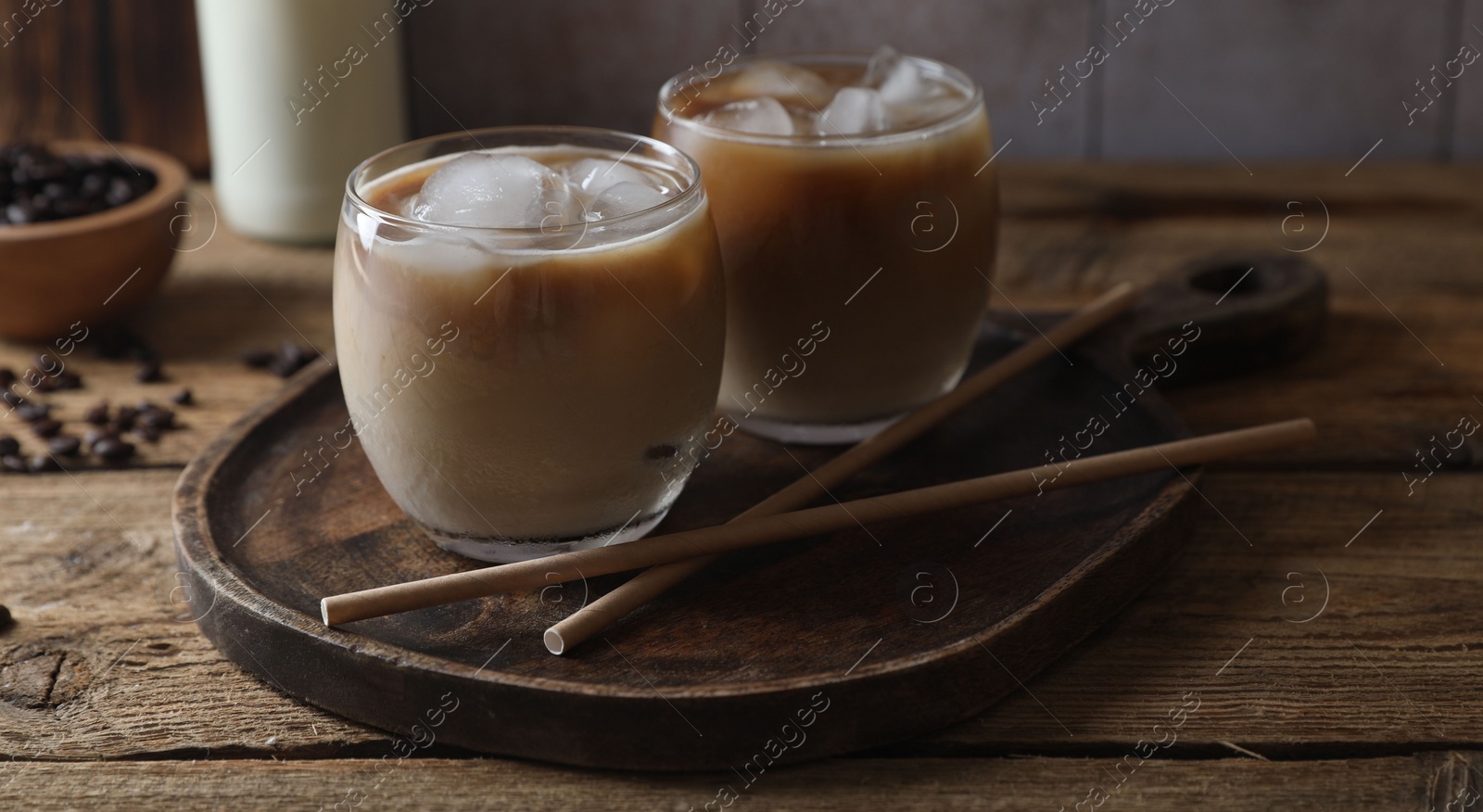 Photo of Refreshing iced coffee with milk in glasses and straws on wooden table