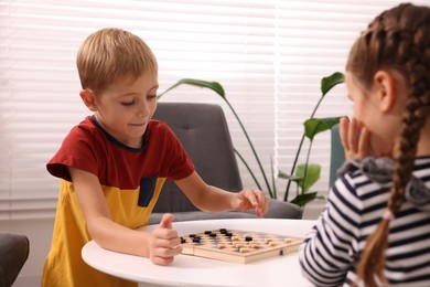 Photo of Children playing checkers at coffee table indoors