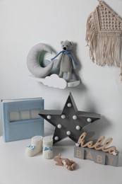 Album, baby shoes and toys on chest of drawers indoors. Children's room interior