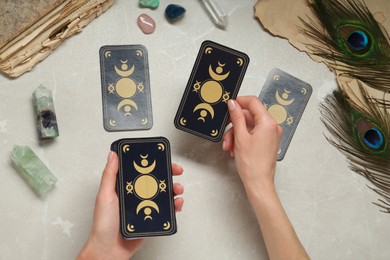 Woman with tarot cards at light table, top view. Reverse side