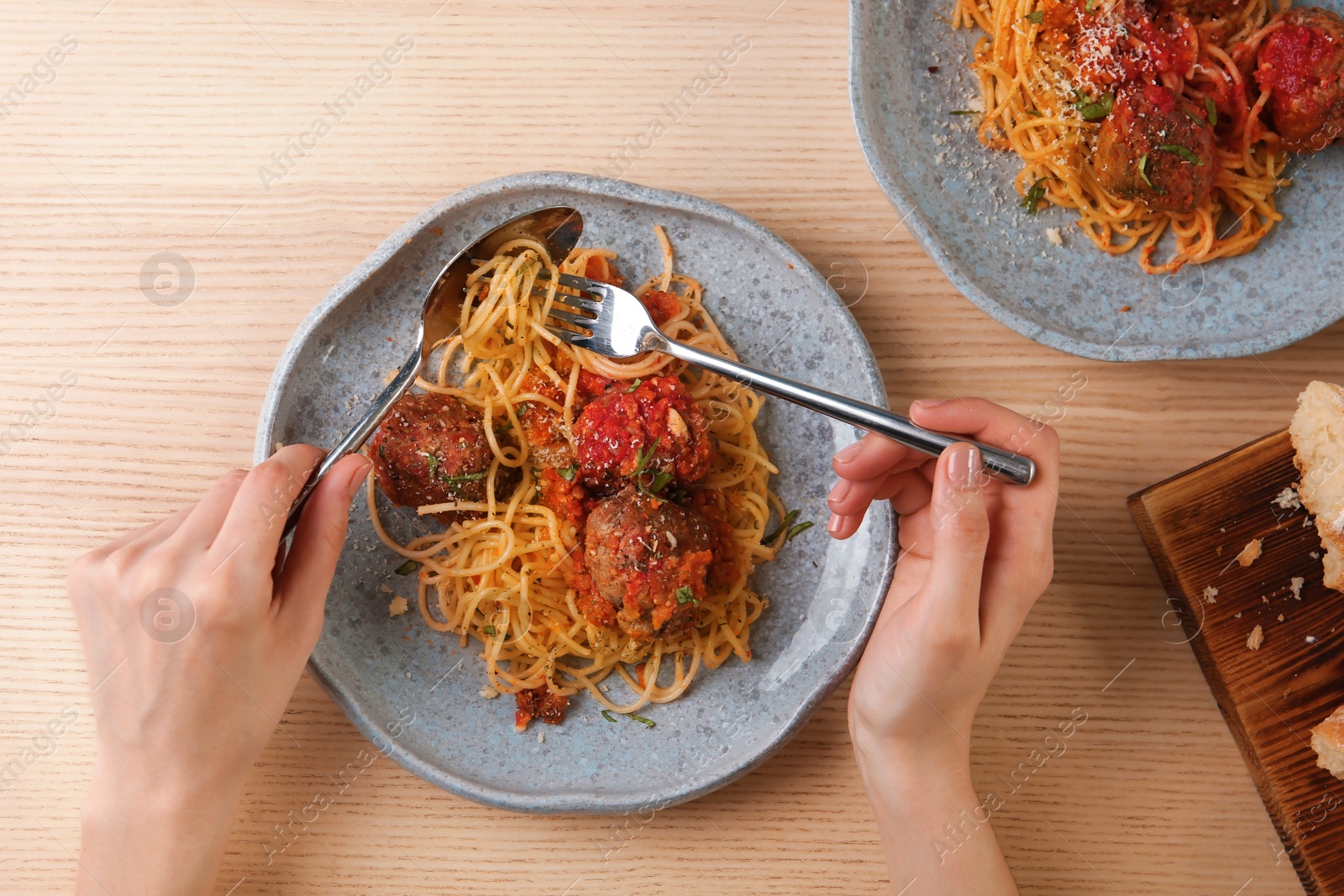 Photo of Woman having pasta with meatballs and tomato sauce at table, closeup