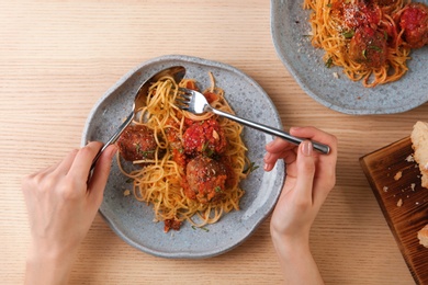 Photo of Woman having pasta with meatballs and tomato sauce at table, closeup