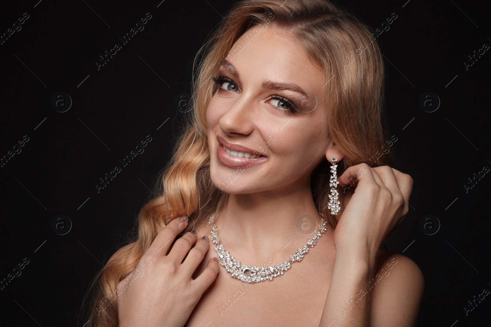 Photo of Beautiful young woman with elegant jewelry on dark background