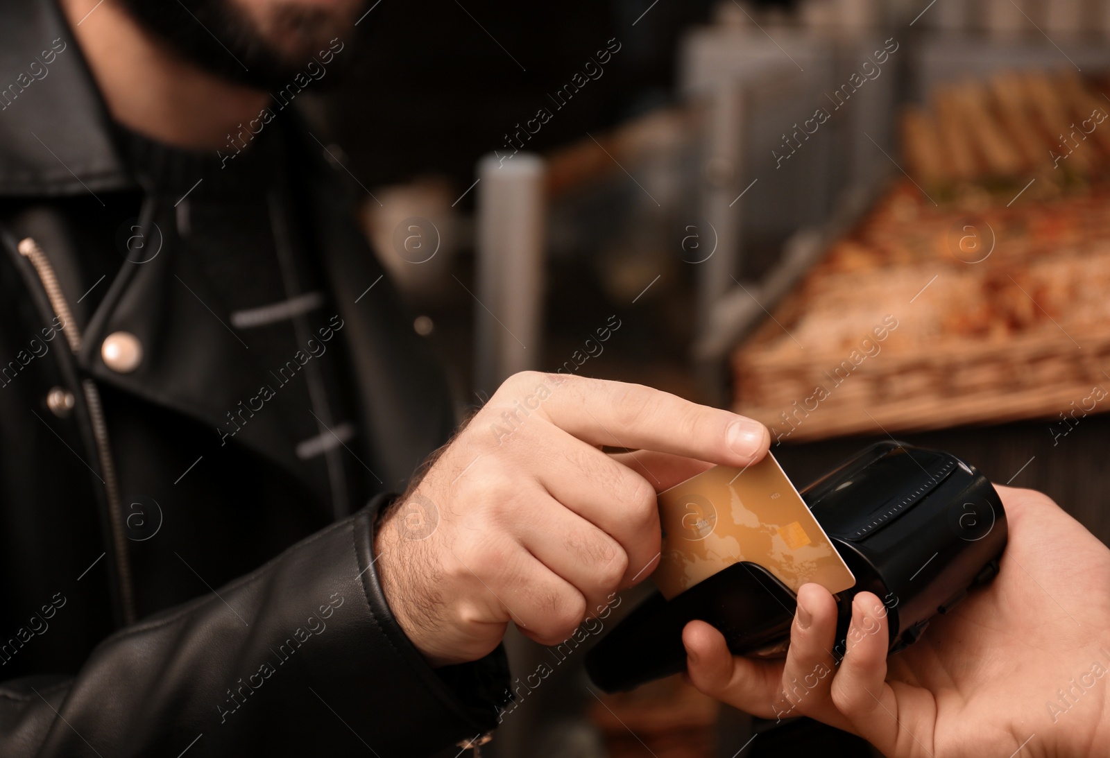 Photo of Man with credit card using payment terminal at shop, closeup