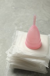 Photo of Menstrual cup and pads on grey table