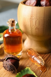 Photo of Horse chestnuts, leaves and bottles of tincture on wooden table