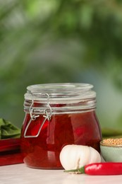 Tasty rhubarb sauce and ingredients on white table against blurred background, space for text