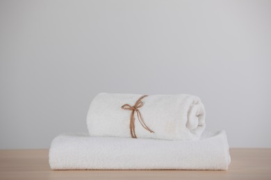 Photo of Rolled and folded soft towels on wooden table