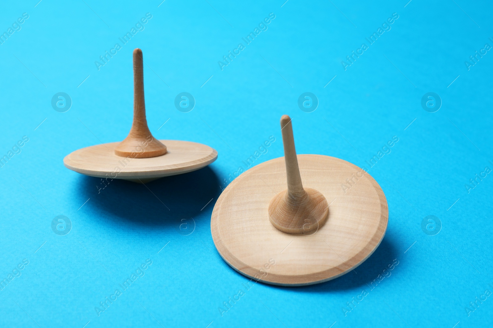 Photo of Two wooden spinning tops on light blue background