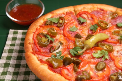 Photo of Delicious pizza Diablo and sauce on green wooden table, closeup