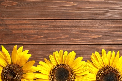 Photo of Beautiful bright sunflowers on wooden background, top view