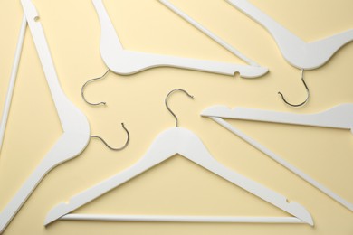 White hangers on pale yellow background, flat lay