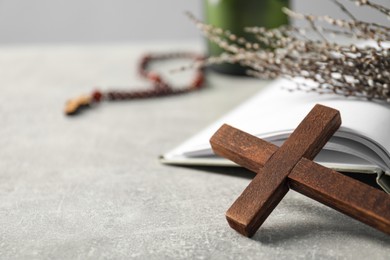 Photo of Wooden cross and Bible on grey table, closeup. Space for text