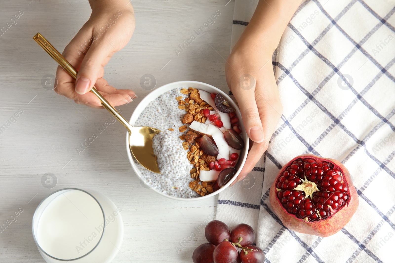 Photo of Young woman eating tasty chia seed pudding at table, top view